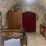 ...ci apre la porta di un luogo con mura in pietra e volte a botte, diviso in due ambienti tramite una tenda rossa di velluto